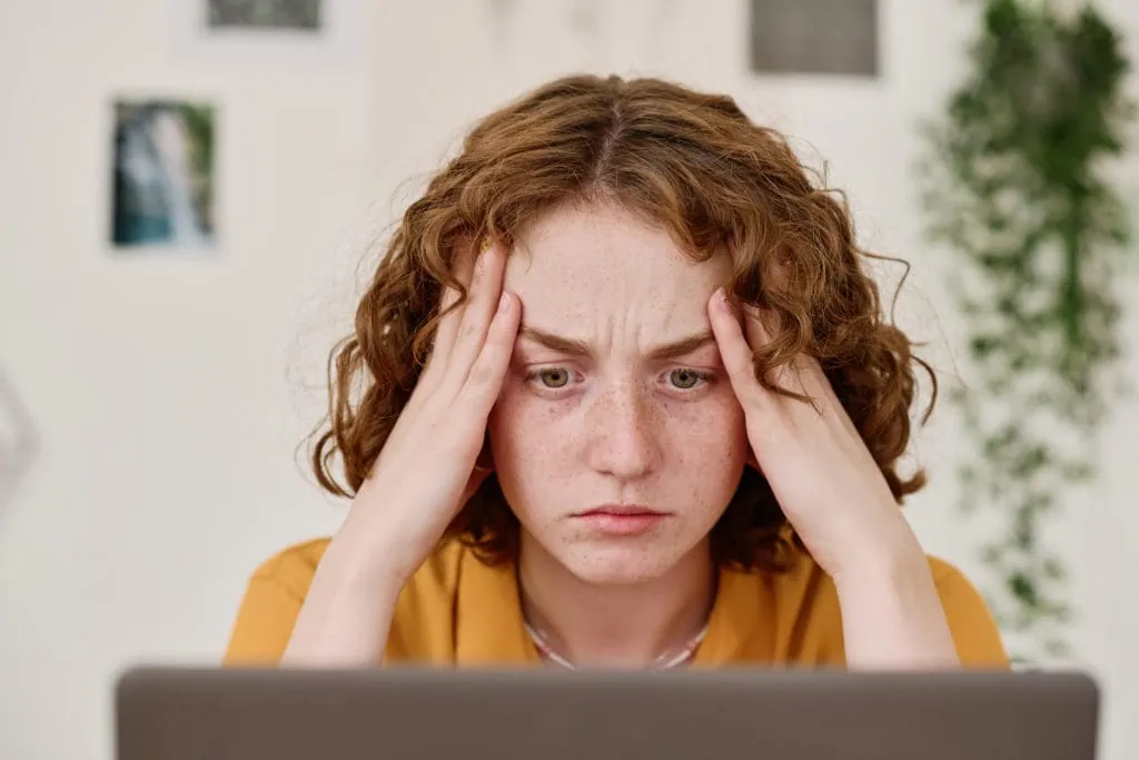 SEO Optimierung: Junge Freiberuflerin mit angespanntem Gesichtsausdruck, die auf einen Laptop-Bildschirm schaut, während sie am Arbeitsplatz sitzt und SEO-Informationen analysiert.