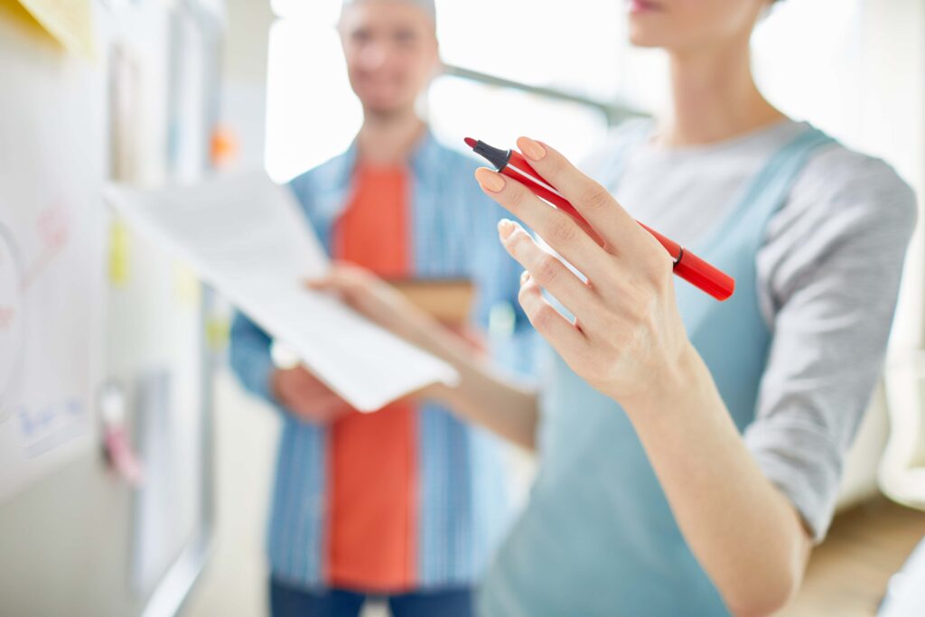 Content Marketing - Nahaufnahme einer Analystin, die einen Filzstift in der Hand hält und über eine Content-Marketing-Strategie spekuliert, während sie Forschungsdaten präsentiert.