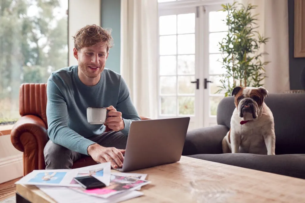 Affiliate Marketing: Mann, der von zu Hause aus in der Kreativdesign- oder Marketingbranche arbeitet, prüft Kunstwerke mit einer Bulldogge
