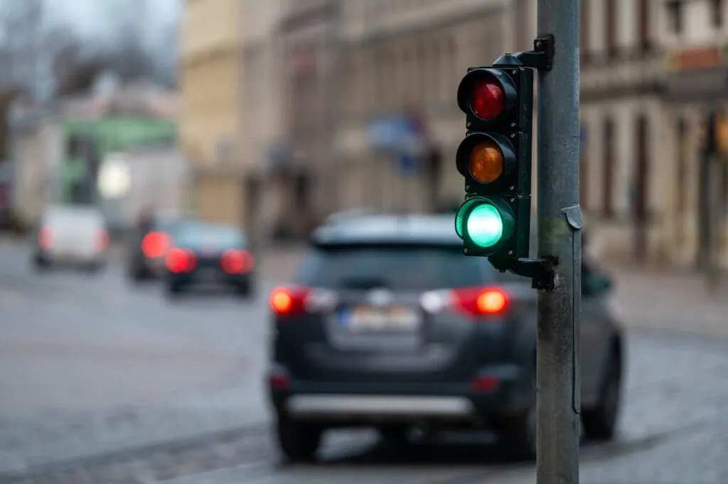 Nahaufnahme einer kleinen Ampel mit grünem Licht vor dem Hintergrund des Stadtverkehrs.